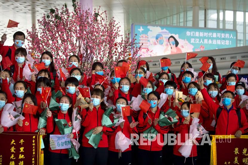 Sejumlah tenaga medis dari Provinsi Jilin mengibarkan bendera Cina ketika bersiap untuk pulang di Bandara Internasional Tianhe Wuhan, Cina