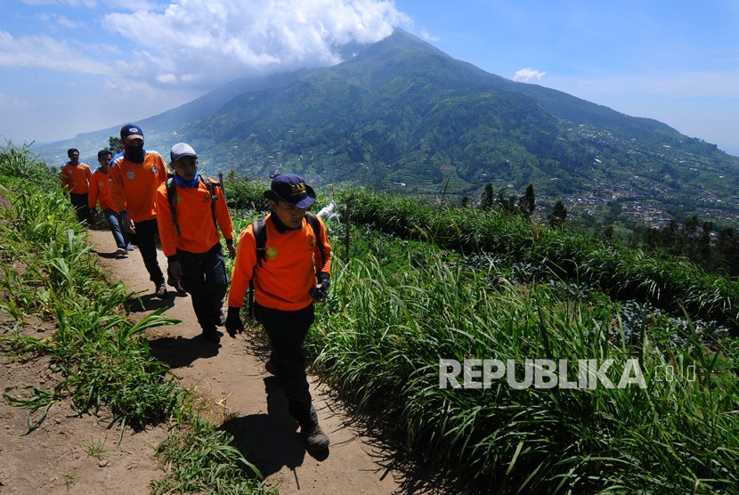 Sejumlah tim evakuasi gabungan melintas dijalur pendaki Gunung Merapi dengan berlatar belakang Gunung Merbabu di Selo, Boyolali, Jawa Tengah, Jumat (11/5).