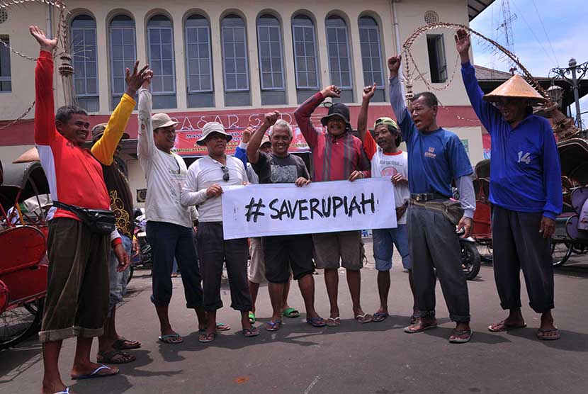 Sejumlah tukang becak membawa spanduk bertuliskan Save Rupiah di Pasar Gede, Solo, Jawa Tengah, Kamis (12/3).  (Antara/Yusuf Nugroho)