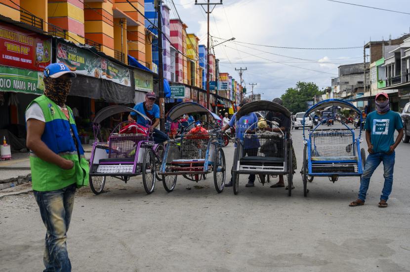 Sejumlah tukang becak menunggu penumpang di salah satu ruas jalan di Palu, Sulawesi Tengah, Ahad (5/4/2020). Pemerintah akan memberikan bantuan sosial kepada 29,3 juta penerima bantuan langsung tunai (BLT) yang tergolong dalam 40 persen warga miskin, termasuk para pekerja informal yang terdampak COVID-19.