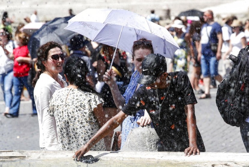 Sejumlah turis mendinginkan diri di dekat air mancur St. Peter Square di Vatikan, Sabtu (29/6). Italia mengeluarkan peringatan panas di 16 kota.