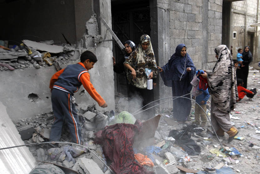  Sejumlah wanita dan anak-anak mengumpulkan barang-barang dari rumah mereka yang hancur akibat serangan udara Israel di kamp pengungsi Jebaliya sebelah Utara Jalur Gaza, Sabtu (17/11).  (AP/Hatem Moussa)