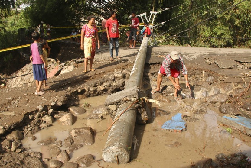 Sejumlah warga berada dekat tiang listrik yang roboh akibat diterjang banjir bandang di Desa Sepit, Keruak, Selong, Lombok Timur, NTB, Ahad (19/11).