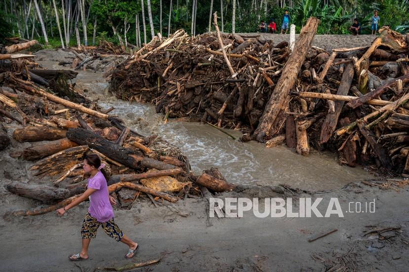Sejumlah warga berada di antara tumpukan potongan kayu yang terbawa saat terjadi banjir bandang di Desa Rogo, Dolo Selatan, Sigi, Sulawesi Tengah, Senin (30/8/2021). Banjir bandang yang terjadi pada Minggu (29/8) malam akibat hujan deras dan menjebol tanggul sungai itu menyapu dan menimbun puluhan rumah warga. 