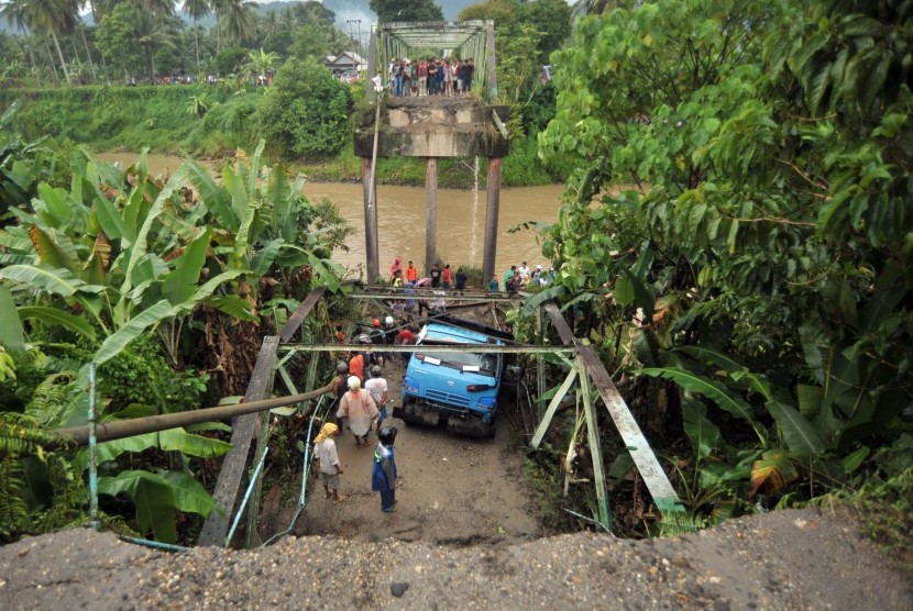 Sejumlah warga berada di dekat mobil truk yang jatuh akibat jembatan yang ambruk, di Nagari Sikabu, Kec.Lubuk Alung, Kab.Padangpariaman, Sumatera Barat, Senin (14/8). 