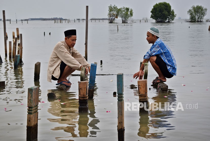 Sejumlah warga berdoa saat berziarah di makam kerabatnya di tempat pemakaman umum (TPU) yang terdampak abrasi di Tambaklorok, Semarang, Jawa Tengah. 