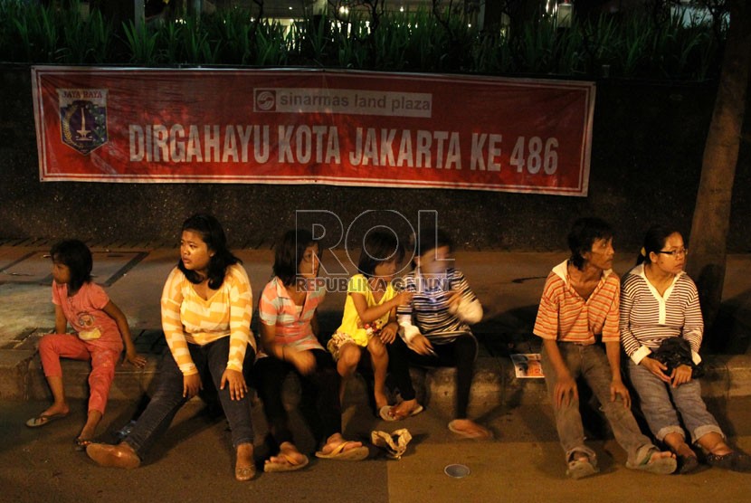   Sejumlah warga beristirahat karena lelah saat perayaan HUT Kota Jakarta ke-486 di Jalan MH Thamrin, Jakarta, Sabtu (22/6).  (Republika/Yasin Habibi)