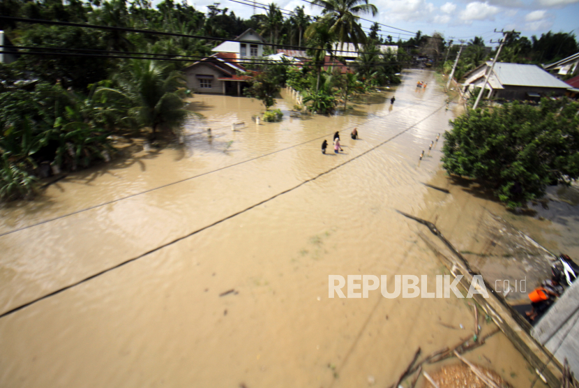 Sejumlah warga berjalan menerobos banjir di Kampung Baru Lhoksukon, Aceh Utara, Aceh, Selasa (4/1/2022). Data terakhir Badan Penanggulangan Bencana Daerah (BPBD) setempat menyebutkan banjir masih melanda 14 Kecamatan dan jumlah pengungsi terdampak bertambah dari 6.633 Kepala Keluarga (KK) atau 24.332 jiwa menjadi 9.766 KK atau 32.854 jiwa. 