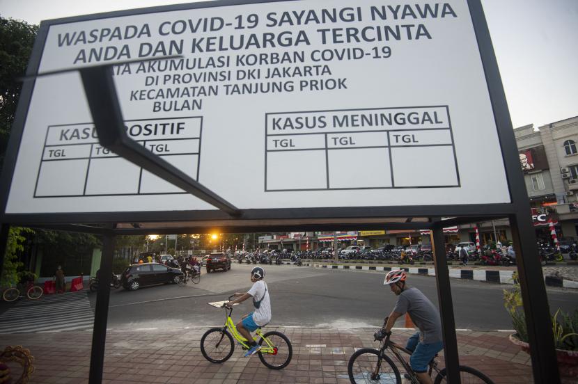 Sejumlah warga bersepeda dengan latar depan papan informasi perkembangan kasus COVID-19 di Sunter, Jakarta, Sabtu (22/8/2020). Data Satuan Tugas Penanganan COVID-19 per hari Sabtu (22/8) pukul 12.00 WIB menyebutkan kasus positif COVID-19 bertambah 2.090 orang sehingga menjadi 151.498 orang, sementara kasus pasien sembuh COVID-19 bertambah 2.207 orang menjadi 105.198 orang.