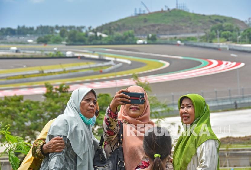 Sejumlah warga berswafoto saat menonton sesi tes pramusim MotoGP 2022 dari atas bukit sekitar Pertamina Mandalika International Street Circuit di KEK Mandalika, Desa Kuta, Kecamatan Pujut, Praya, Lombok Tengah, NTB, Sabtu (12/2/2022). 