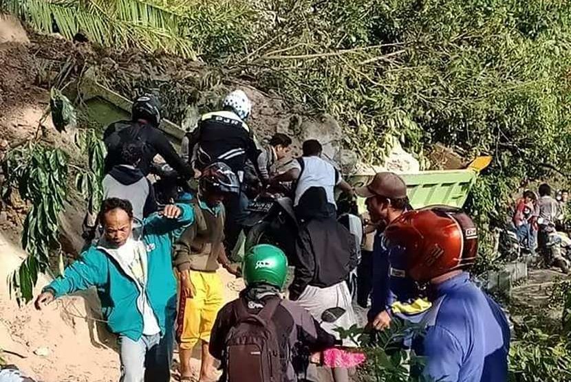 Sejumlah warga berusaha melintasi jalan yang tertutup material tanah longsor di kawasan Kebun Kopi, Kota Palu di Sulawesi Tengah, Sabtu (29/9).