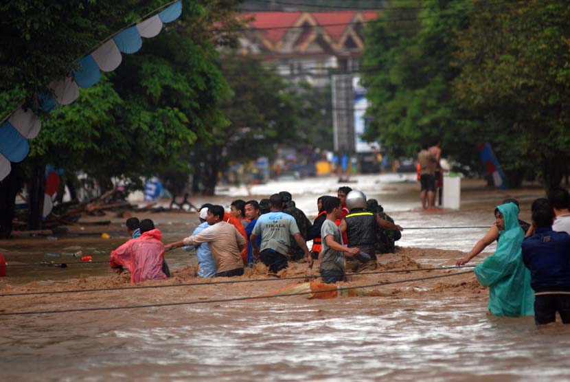   Sejumlah warga berusaha menyeberangi banjir menggunakan tali di Kelurahan Wenang, Manado, Sulawesi Utara, Rabu (15/1).   (Antara/Fiqman Sunandar)