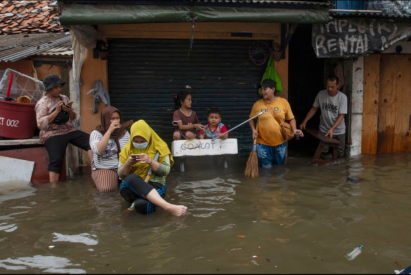 Sejumlah warga duduk di depan rumah mereka yang terendam banjir pasang air laut atau rob di Ancol, Pademangan, Jakarta, Sabtu (4/12)