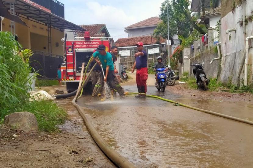 Sejumlah warga Kampung Ciseah, Kecamatan Kutawaringin, Kabupaten Bandung dan petugas pemadam kebakaran tengah membersihkan sisa lumpur dan sampah di pemukiman akibat banjir yang terjadi, Senin (14/11/2022) malam. 