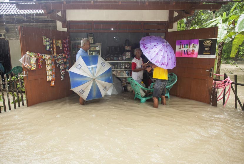 Sejumlah warga melakukan aktivitas jual beli ketika banjir menggenangi pemukiman di Desa Gotakan, Panjatan, Kulon Progo, Yogyakarta, Jumat (20/12).   (Antara/Sigid Kurniawan)