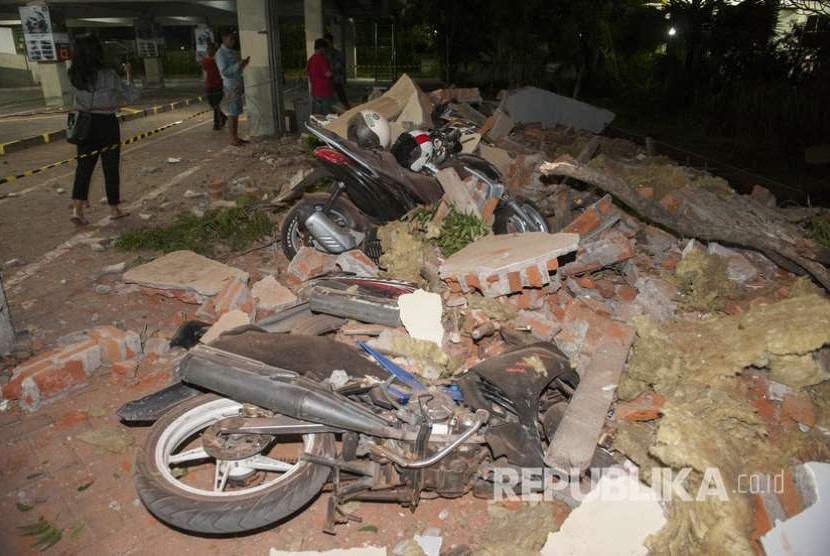 Sejumlah warga melihat reruntuhan bangunan akibat gempa yang menimpa kendaraan di salah satu pusat perbelanjaan di Denpasar, Bali, Ahad (5/8). 