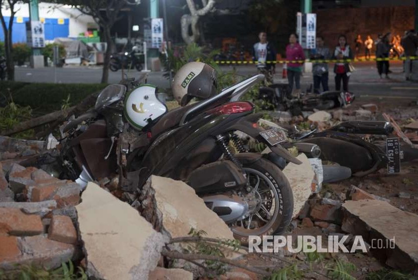 Sejumlah warga melihat reruntuhan bangunan akibat gempa yang menimpa kendaraan di salah satu pusat perbelanjaan di Denpasar, Bali, Ahad (5/8). 