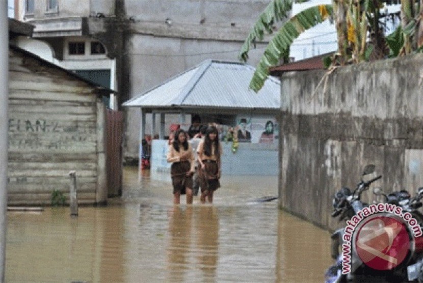 Sejumlah warga melintas banjir di Jambi, Ahad  (17/2). Hujan turun terus-menerus di Jambi dalam sepekan ini mengakibatkan debit air sungai naik sehingga rumah warga di pinggiran Sungai Batanghari terendam.