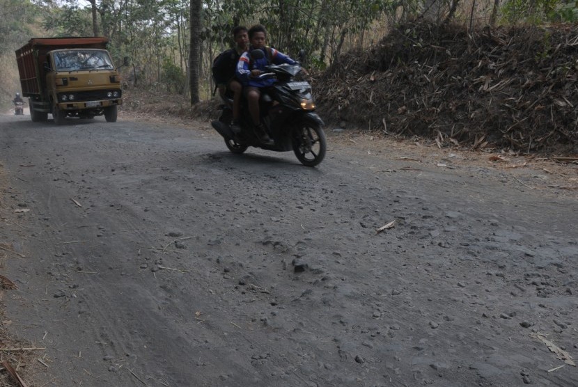 Sejumlah warga melintas di jalur evakuasi Merapi yang rusak di lereng gunung Merapi, Kemalang, Klaten, Jawa Tengah, Jumat (30/10).