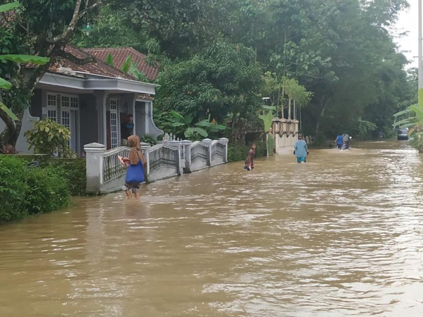 Sejumlah warga melintas jalan yang tergenang banjir di Desa Tanjungsari, Kecamatan Sukaresik, Kabupaten Tasikmalaya, Rabu (13/1).