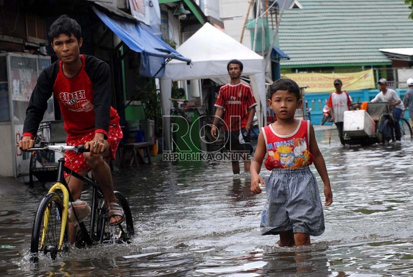  Sejumlah warga melintasi air banjir yang menggenangi pemukiman warga di Muara Angke, Jakarta Utara, Kamis (13/12).   (Republika/Agung Fatma Putra)