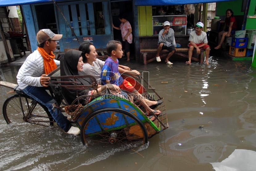  Sejumlah warga melintasi air banjir yang menggenangi pemukiman warga di Muara Angke, Jakarta Utara, Kamis (13/12).   (Republika/Agung Fatma Putra)