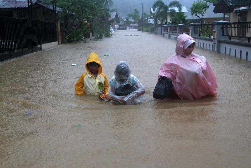 Sejumlah warga melintasi banjir yang melanda daerah Jondul Rawang Barat, Padang, Sumatera Barat, Rabu (26/9). 