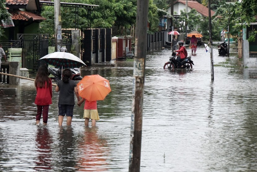 Sejumlah warga melintasi genangan air yang membanjiri jalan, di desa Mertasinga, Cilacap Utara, Cilacap, Jateng (ilustrasi) 