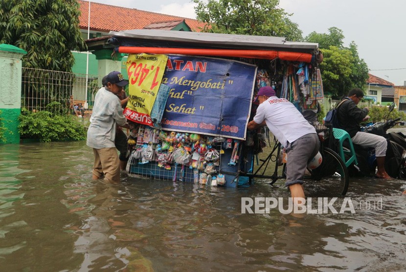 Sejumlah warga melintasi jalan yang terimbas banjir, Kamis (15/2).
