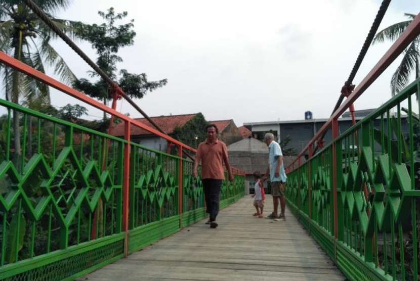 Sejumlah warga melintasi jembatan gantung 'Indiana Jones', di Kelurahan Srengseng Sawah, Kecamatan Jagakarsa, Kota Jakarta Selatan, Rabu (13/2).