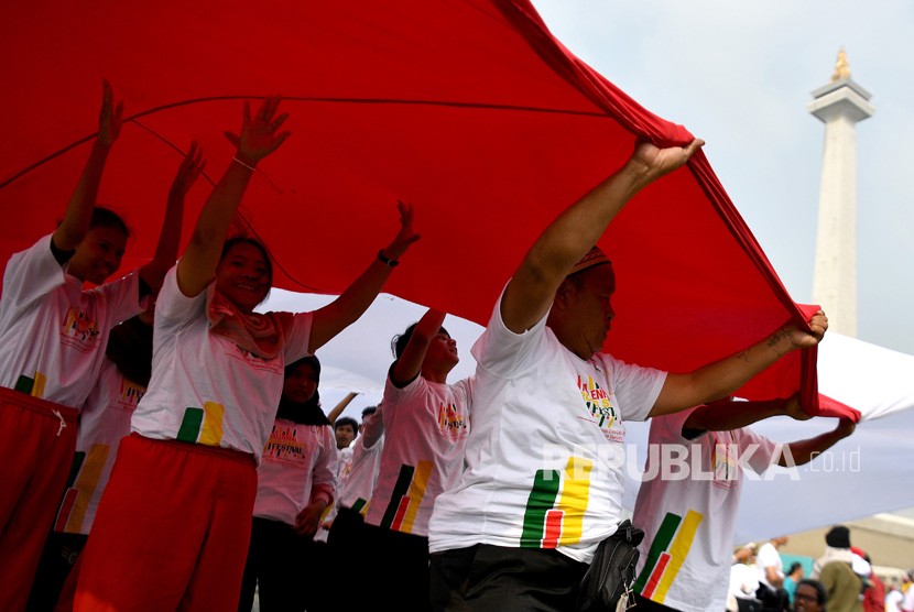 Sejumlah warga membentangkan bendera Merah-Putih dalam Festival Damai dan Millennial Safety Road di Monas, Jakarta Pusat, Ahad (23/6/2019). 