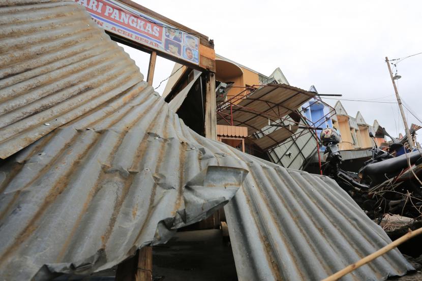 Sejumlah warga membersihkan dan membenahi atap seng kios yang rusak akibat angin kencang dan cuaca ekstrem. (Ilustrasi)