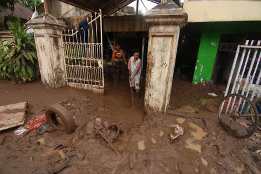 Sejumlah warga membersihkan lumpur rumahnya setelah terendam banjir.