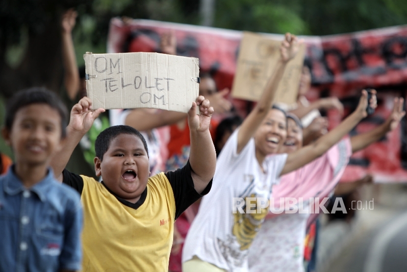 Sejumlah warga memegang poster bertuliskan Om Telolet Om saat menanti bus yang melintas membunyikan Klakson Telolet di Jalan Raya Bogor, Jakarta TImur, Ahad (25/12). 