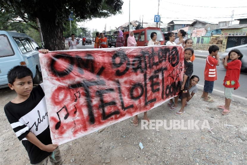 Sejumlah warga memegang poster bertuliskan Om Telolet Om saat menanti bus yang melintas membunyikan Klakson Telolet di Jalan Raya Bogor, Jakarta TImur, Ahad (25/12).