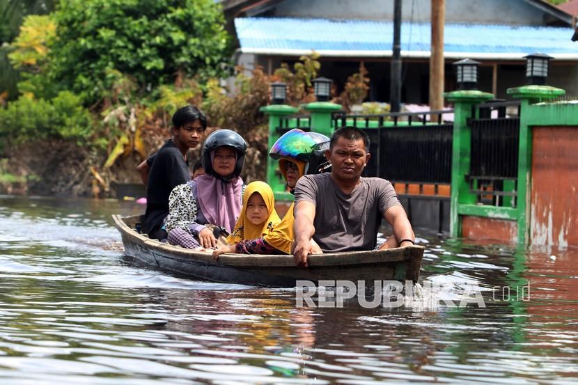 Sejumlah warga menaiki perahu motor saat melintasi banjir di Kelurahan Ulak Jaya, Sintang, Kalimantan Barat, Ahad (21/11/2021). Banjir yang melanda kelurahan Ulak Jaya selama hampir empat pekan dengan ketinggian air dua meter tersebut sudah semakin surut. 