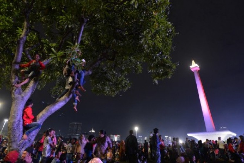 Sejumlah warga menaiki pohon untuk menyaksikan hiburan dalam rangka menyambut pergantian tahun di Monas, Jakarta, Ahad (31/12). 