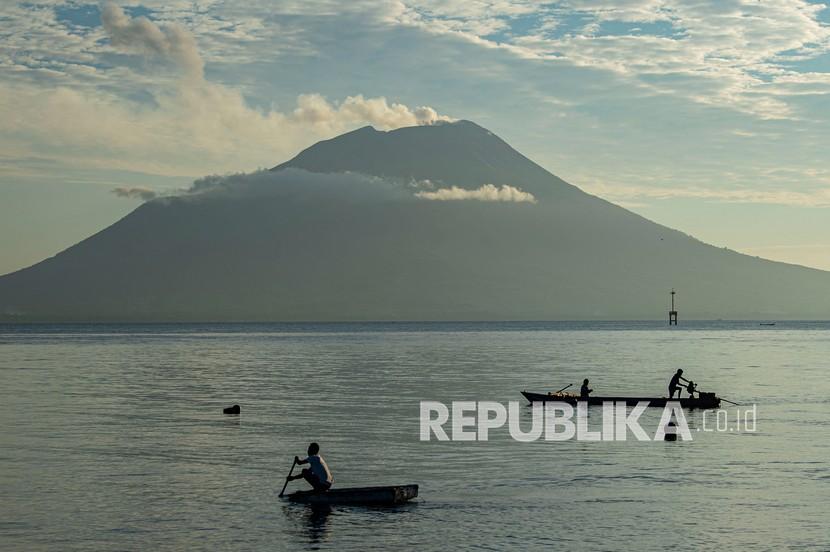 Warga mendayung perahu di perairan dengan latar Gunung Ile Ape di Kabupaten Lembata, Nusa Tenggara Timur (NTT).