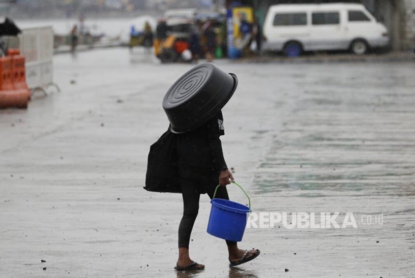 Sejumlah warga menggunakan baskom sebagi payung menghindari hujan lebat akibat Badai Kammuri yang menghantam Manila, Selasa (3/12). Pemerintah Filipina mengatakan korban tewas badai Kammuri menjadi 13 orang.