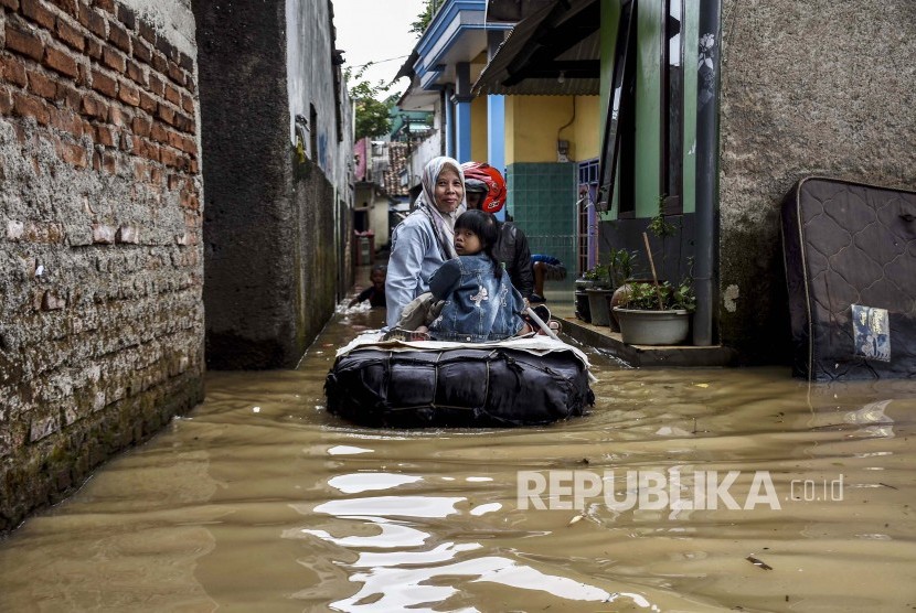 Sejumlah warga menggunakan rakit melintasi genangan banjir di Kampung Bojongasih, Kecamatan Dayeuhkolot, Kabupaten Bandung, Jumat (24/1).