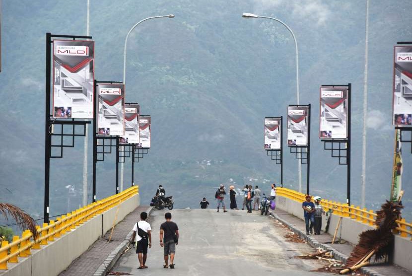 Sejumlah warga menikmati suasana pagi di ujung jembatan kuning yang rusak akibat diterjang tsunami di Pantai Talise Palu, Sulawesi Tengah, Sabtu (13/10).