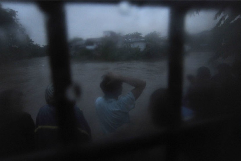 Sejumlah warga menonton banjir yang melanda bantaran sungai Ciliwung di kawasan Kampung Melayu, Jakarta, Selasa (15/1).