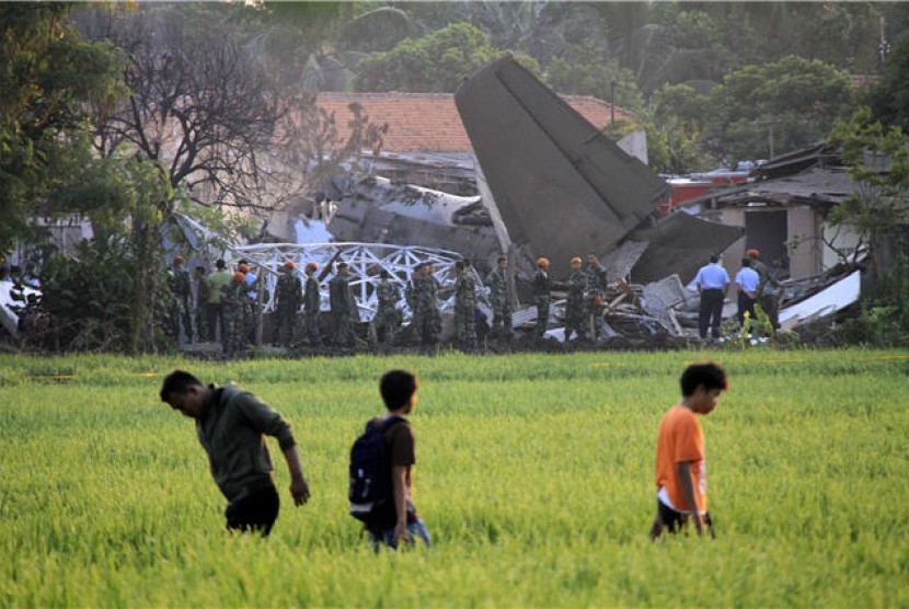 Sejumlah warga menyaksikan bangkai pesawat Fokker 27 yang jatuh di komplek Rajawali, Lapangan Udara Halim Perdana Kusuma, Jakarta, Kamis (21/6). 