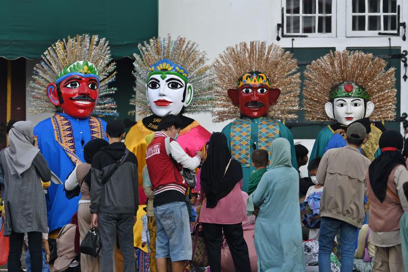 Sejumlah warga menyaksikan kesenian Ondel-ondel dalam memeriahkan hari ulang tahun (HUT) ke-495 Jakarta di kawasan Kota Tua, Jakarta Barat, Ahad (19/6/2022). 