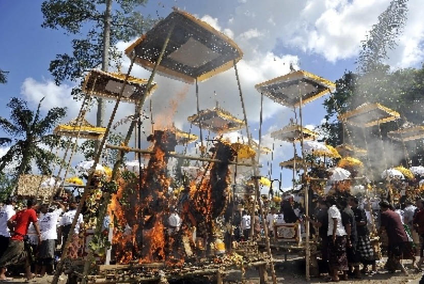 Sejumlah warga menyaksikan pembakaran peti mati berbentuk singa dan sapi yang berisi jenazah anggota keluarganya dalam Ngaben massal di Desa Kedewatan, Ubud, Bali, Minggu (18/8). 