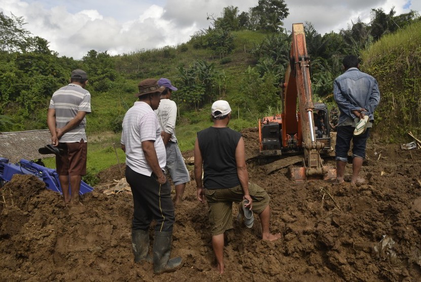 Sejumlah warga menyaksikan proses pencarian jenazah korban di lokasi tanah longsor di Kelurahan Paal 4, Tikala, Manado, Sulawesi Utara, Jumat (16/12). 