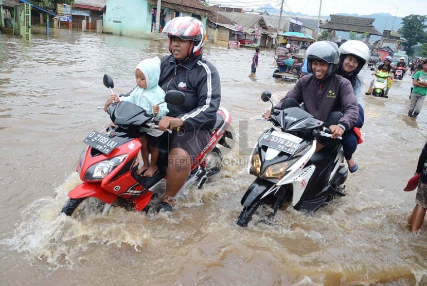   Sejumlah warga nekat melintasi jalan raya yang sudah terendam banjir di Jl Cieunteung, Kecamatan Baleendah, Kabupaten Bandung, Ahad (15/12).  (Republika/Edi Yusuf)