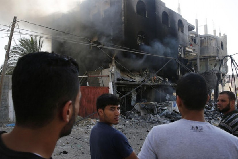 Sejumlah warga Palestina berkumpul di dekat bangunan yang hancur akibat rudal Israel di Gaza City, Jalur Gaza.