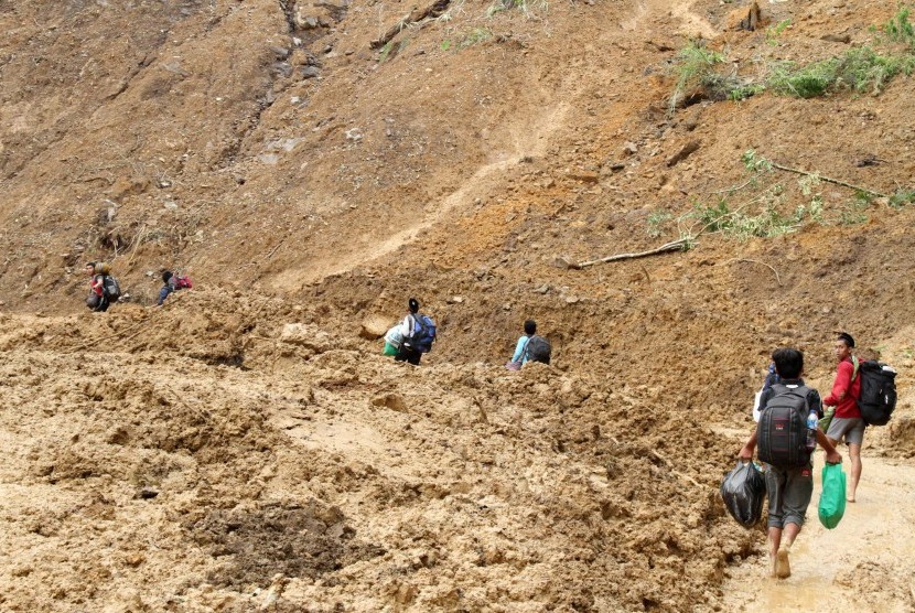 Sejumlah warga terpaksa berjalan kaki akibat jalan raya tertutup longsoran tanah. 