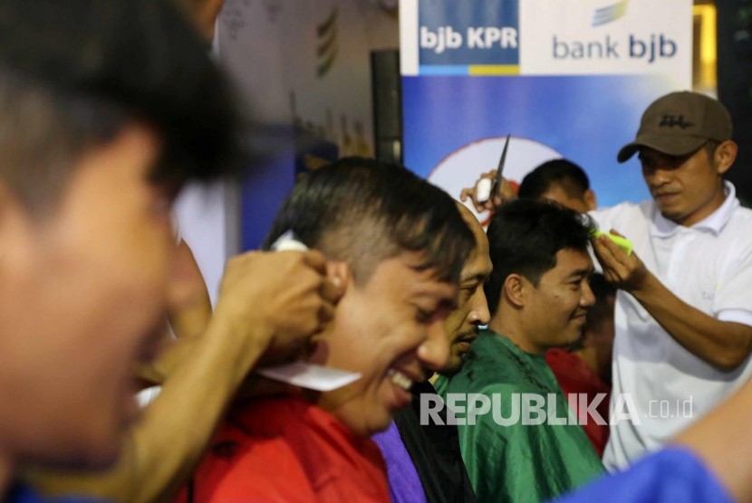 Sejumlah wartawan peliput PON XIX potong rambut bersama-sama di booth cukur rambut Bank BJB di Media Center Utama (MCU) di Trans Hotel, Kota Bandung, Selasa (22/9). Kegiatan tersebut untuk menyemarakan PON XIX. (Republika/Edi Yusuf)